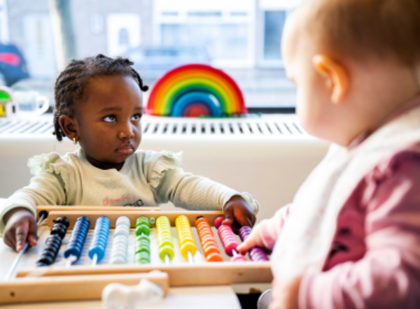 2 peuters spelen met een telraam in allerlei felle kleuren