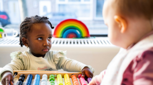 2 peuters spelen met een telraam in allerlei felle kleuren