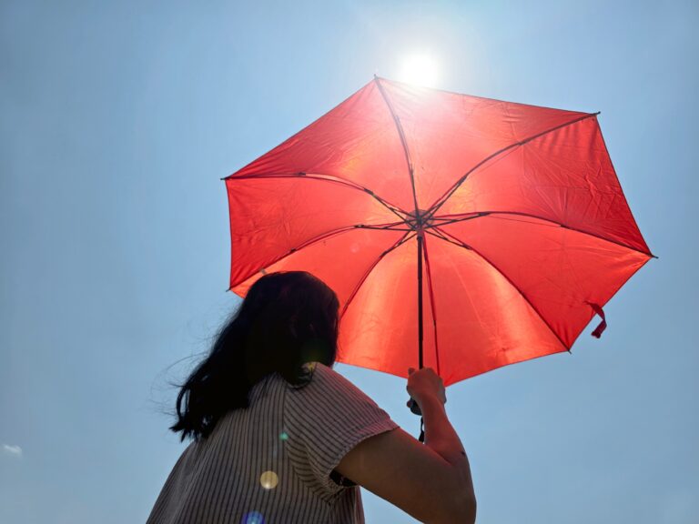 Vrouw houdt oranje parasol vast boven haar hoofd